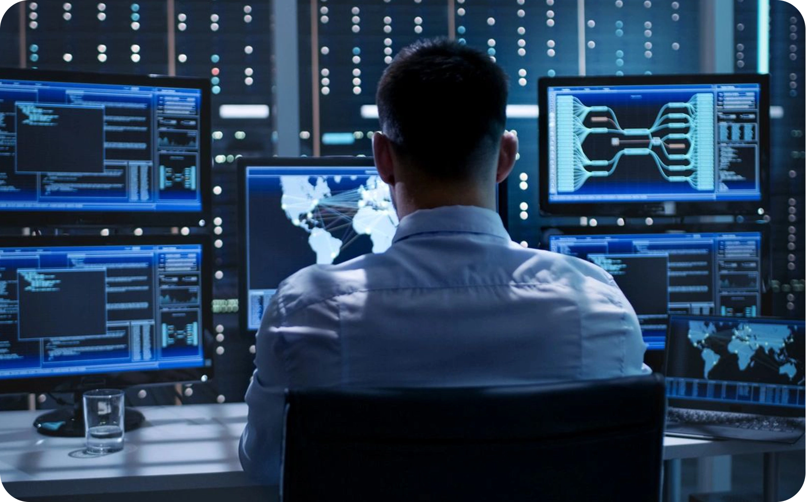 man sitting in chair in front of several monitors