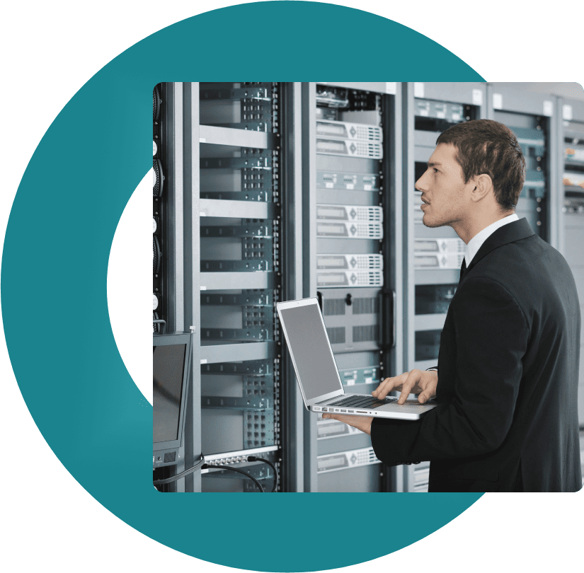 A man in suit and tie standing next to server racks.