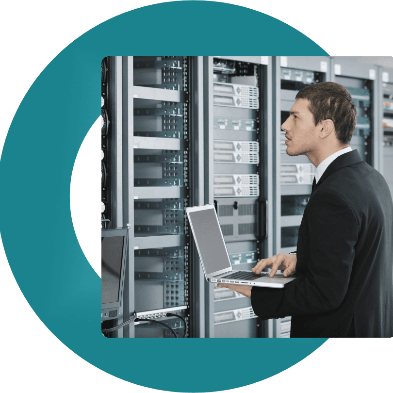 A man in suit and tie standing next to server racks.